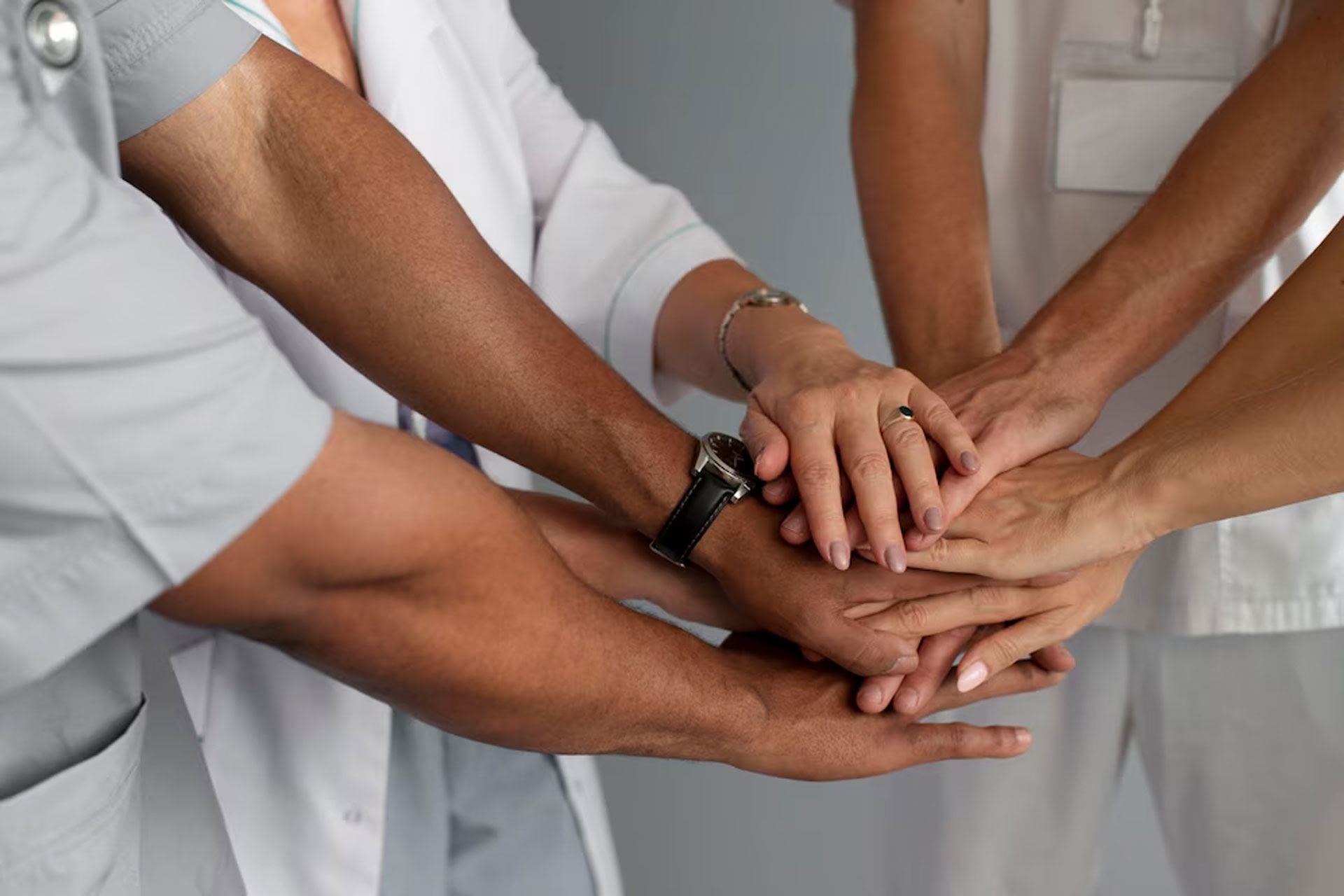 A team of home carers placing their hands on top of each others. Happy care staff means better care, less turnover and lower recruitment costs.