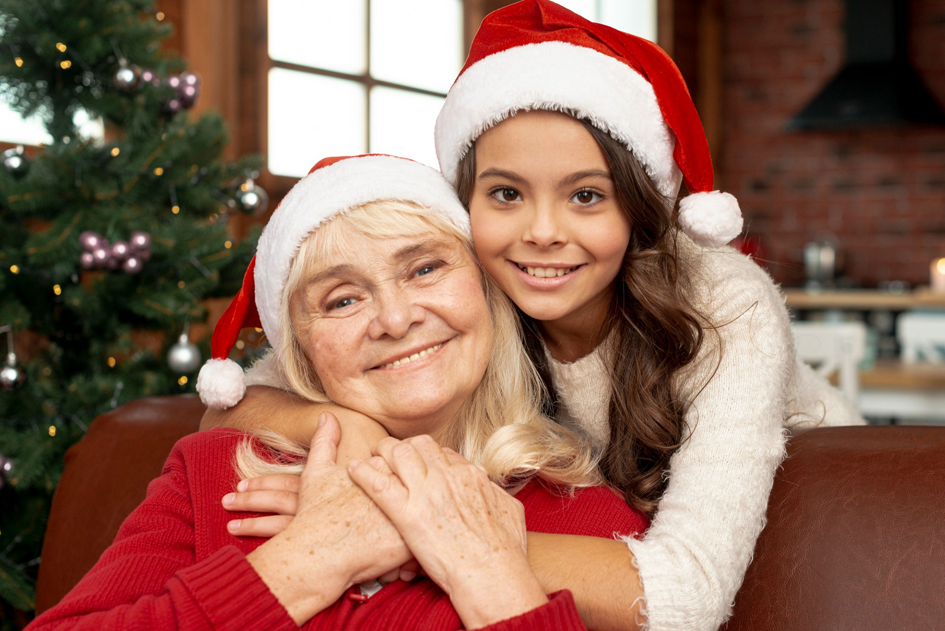 A grandmother enjoying Christmas celebrations with her granddaughter with a decorated tree in the background.