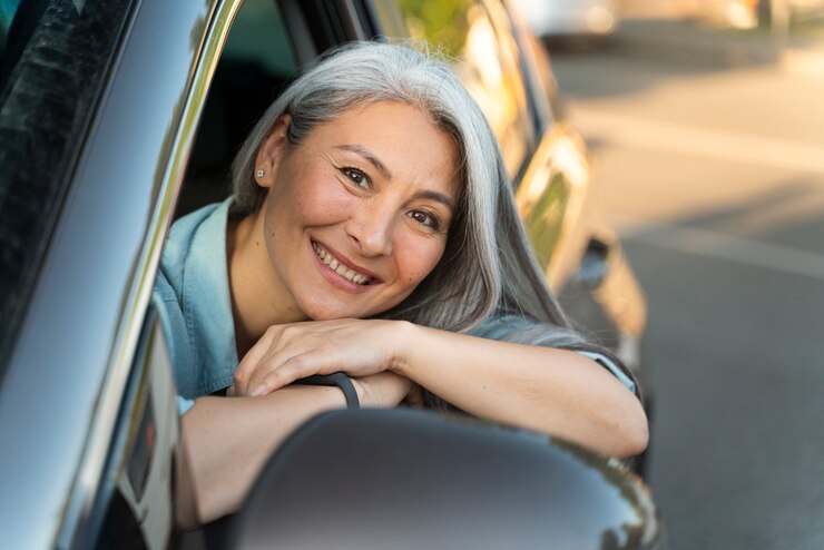 A home care agency worker leaning out of her car window and smiling as she benefits from Fair Mileage Reimbursement.